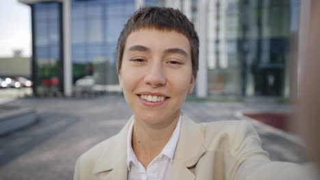 smiling woman taking a selfie outside office building