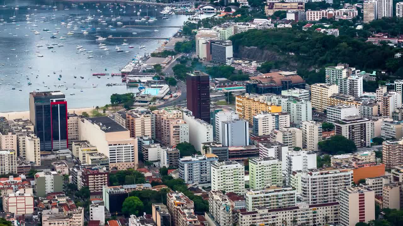 Filmato time-lapse di una vivace città costiera edificata lungo il litorale. I palazzi a media e alta altezza, densamente raggruppati, mostrano diversi stili architettonici e colori.