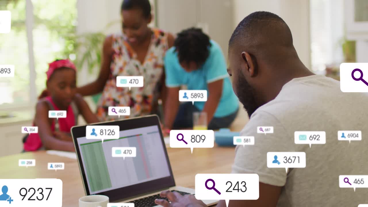 African american businessman using laptop while family in background, icons of increasing followers