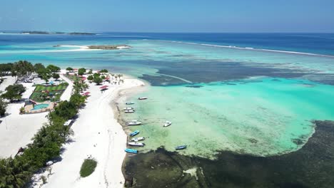 Aerial view of a pristine tropical beach with boats, clear blue waters, and scenic coastline.