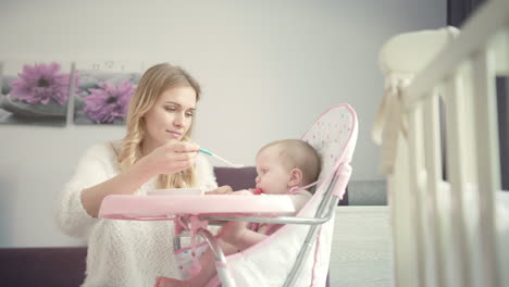 mamá hermosa trata de alimentar al bebé con avena. el bebé roe los dientes