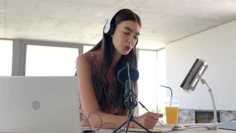 una adolescente caucásica con el pelo largo y marrón está grabando un podcast.