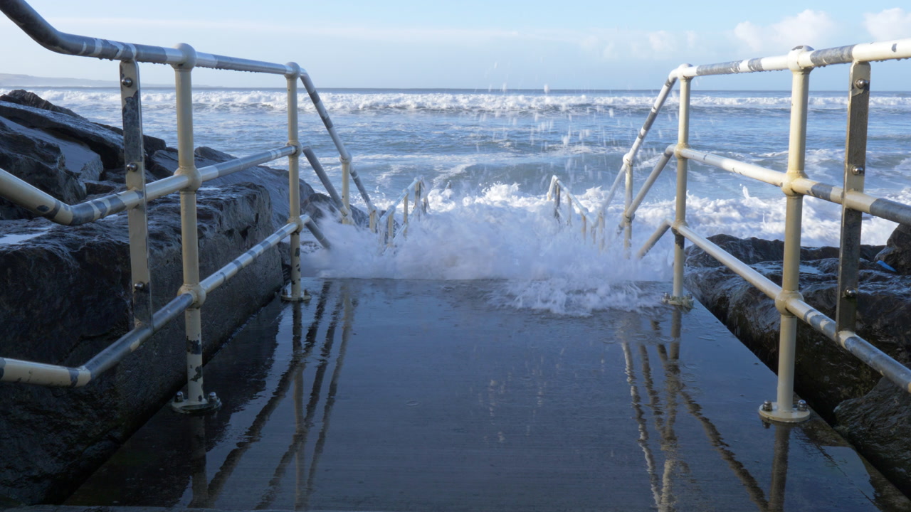 Waves crash on rocky Lahinch beach shore in Ireland, evoking power and nature