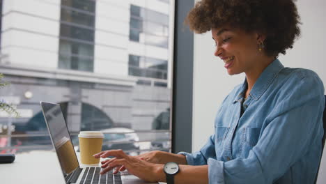 Mujer-De-Negocios-En-Una-Oficina-Moderna-Trabajando-En-Una-Computadora-Portátil-Y-Contestando-Un-Teléfono-Móvil