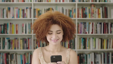 Portrait-Young-woman-student-using-smart-phone-bookshelf-library-university