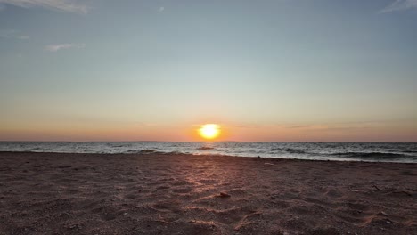 Witness-the-breathtaking-sunset-as-the-sun-dips-below-the-horizon-of-the-Sea-of-Azov,-casting-beautiful-colors-across-the-sky-and-calm-waters