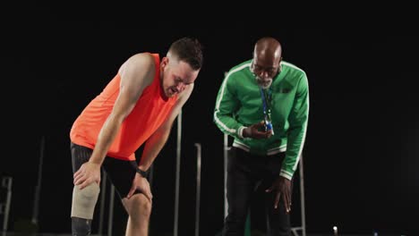 entrenador masculino diverso y cansado atleta masculino discapacitado con cuchilla de correr hablando