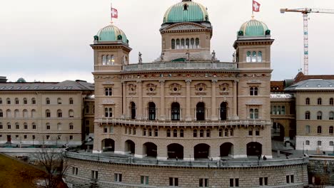 aerial establishing of bern parliament building with swiss flags flying