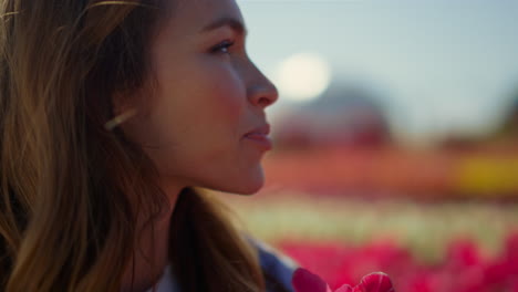 closeup woman face looking at fresh spring flower. happy woman holding red tulip