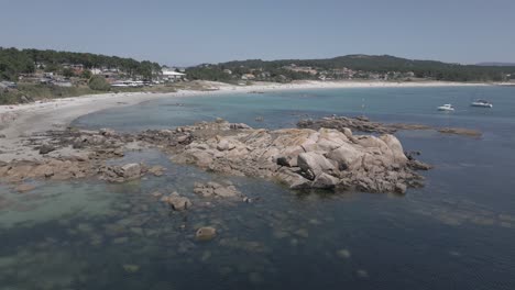 Raw-Aerial-Footage-of-Rocky-Shore-with-Clear-Water-Beach-and-Sailboats