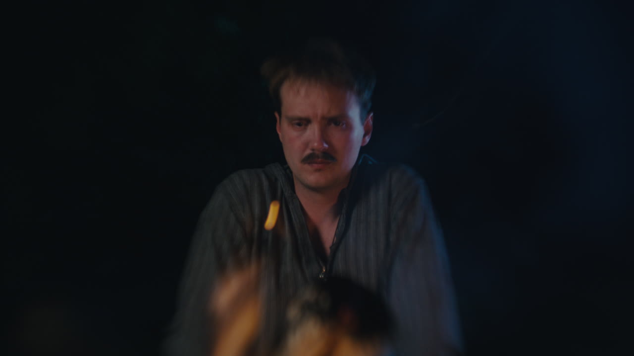 Man with Mustache Looking Down in a Dark Setting
