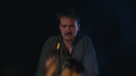 man with mustache looking down in a dark setting