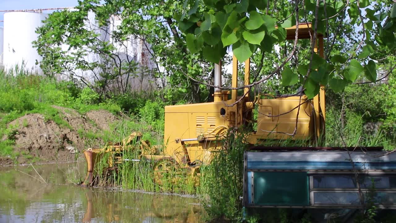 Attrezzatura da costruzione abbandonata giace in acqua stagnante mentre arrugginisce.