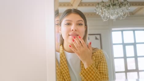 joven mujer caucásica mirándose en el espejo a su cara y tocar la piel, tratamiento de belleza, concepto de cuidado de la piel.
