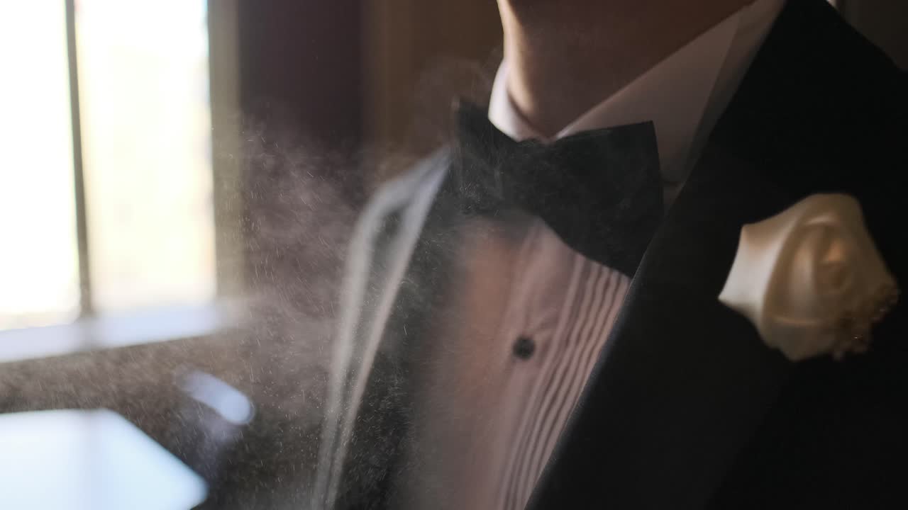 한 남자가 향수를 고르고, 향수를 사용하는 정장을 입은 우아한 남자, 결혼식 전에 아침에 준비하는 신랑