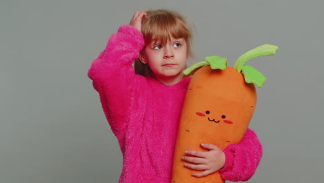 little girl playing with a carrot plush toy