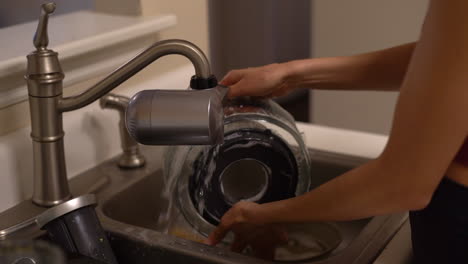 woman's delicate hands seen washing dishes - parts of a juicer - in the kitchen sink in slow motion