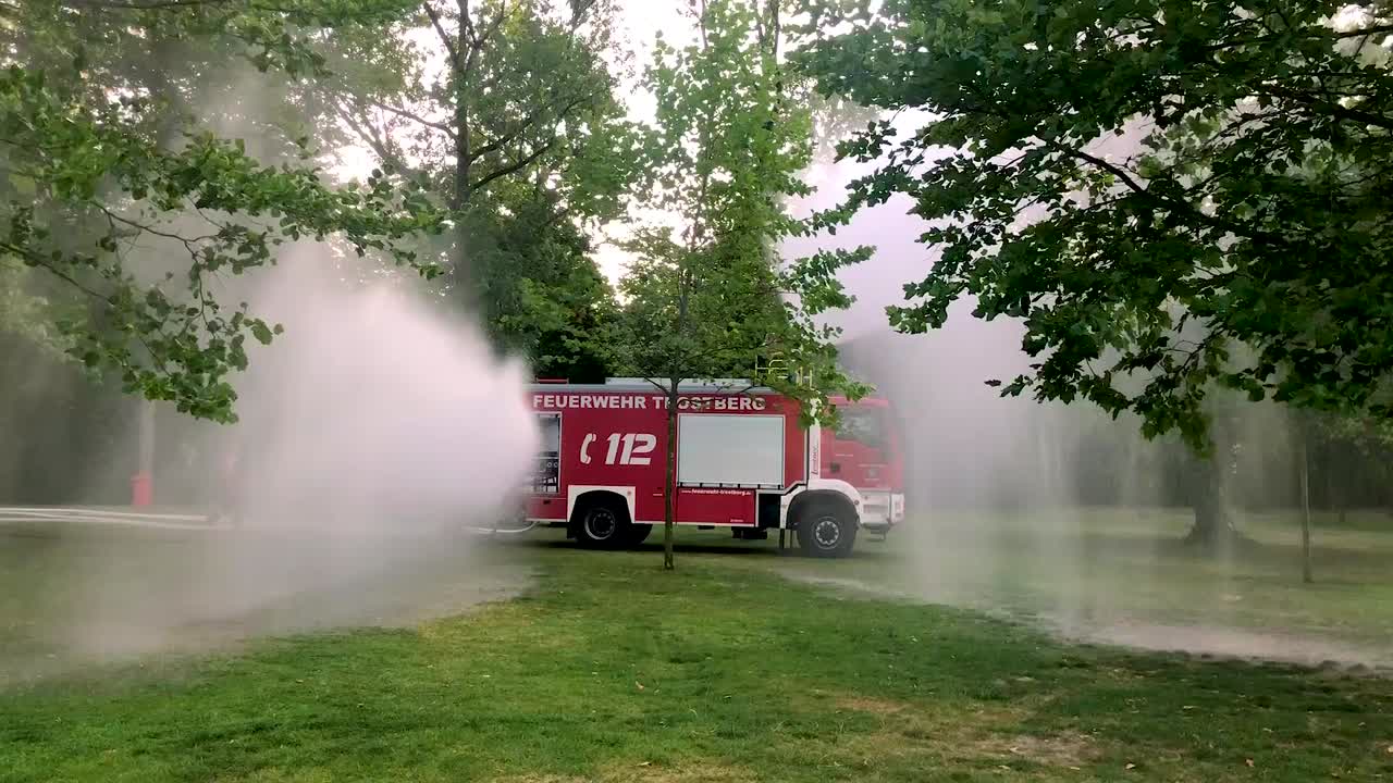 camión de bomberos alemán rociando agua para niños y árboles en un caluroso día de verano-4