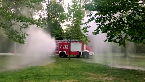 Deutsches-Feuerwehrauto,-Das-An-Einem-Heißen-Sommertag-Wasser-Für-Kinder-Und-Bäume-Sprüht-4