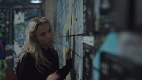 city girl moving body near building wall in urban area at night.