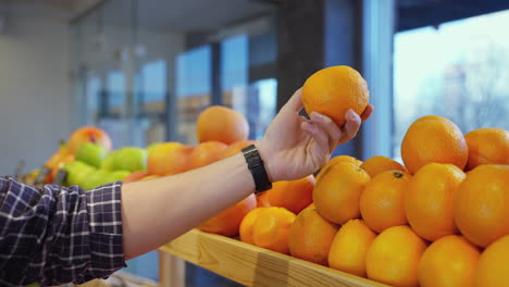persona seleccionando naranjas en una tienda de comestibles