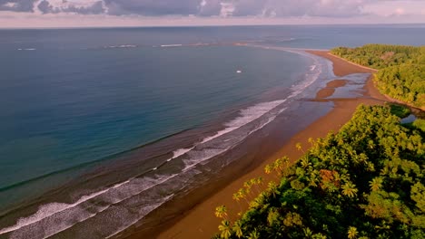 aerial view of uvita, costa rica's wide tropical beach and ocean, featuring clear waters and lush palm forests, all bathed in the gentle light of sunrise