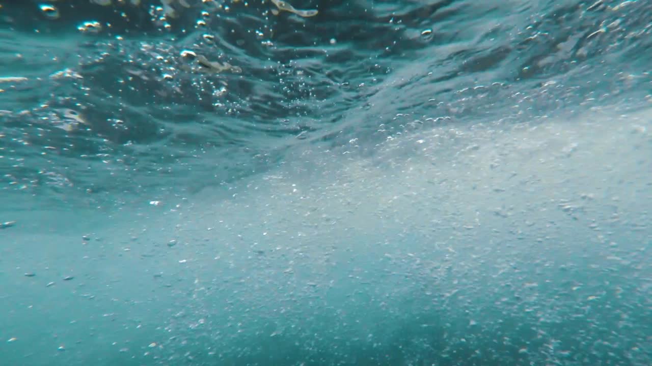 camera diving underwater into and out of a fast moving and rocky river, great transition shot