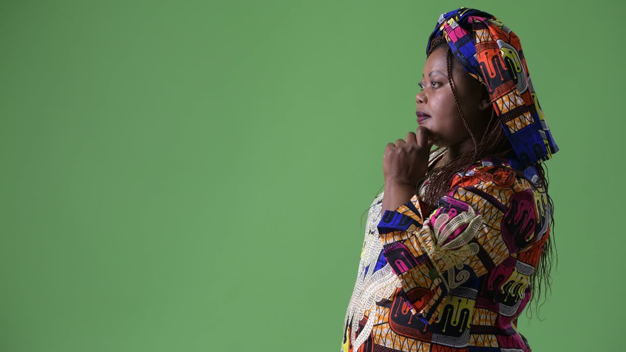 una hermosa mujer africana con sobrepeso que lleva ropa tradicional contra un fondo verde