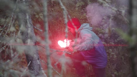 person signaling with red smoke flare in a forest