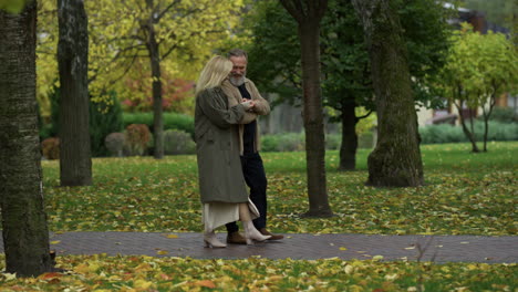 amantes felices caminando por el camino entre los árboles de otoño