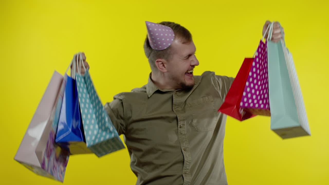 쇼핑 가방을 들어 올리는 남자, 구매에 만족하는 모습, 블랙 프라이데이에 할인을 즐기는 모습