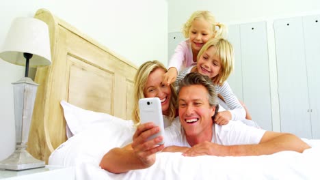 Happy-family-taking-a-selfie-on-mobile-phone-in-the-bed-room-4k