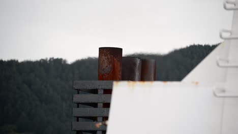 tight shot of rusty ship exhausts blowing out hot, shimmering fumes