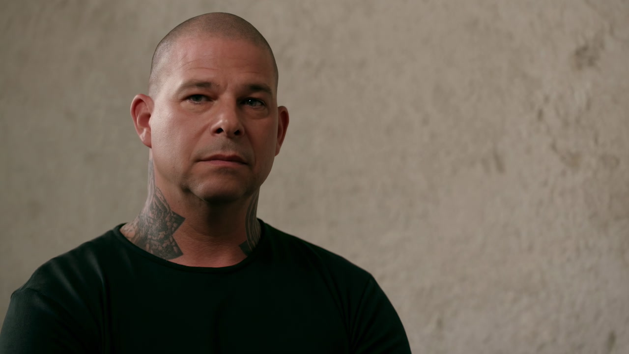 Bald Man with Neck Tattoos Looking Seriously at Camera