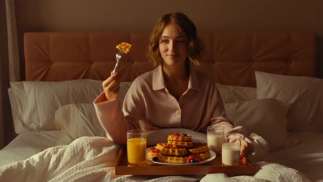 woman eating waffles in bed