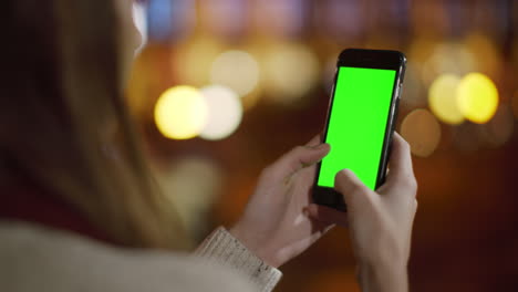 back view girl using phone green screen. woman hands using mock up phone outside