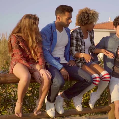 diverse group of five friends sitting on fence