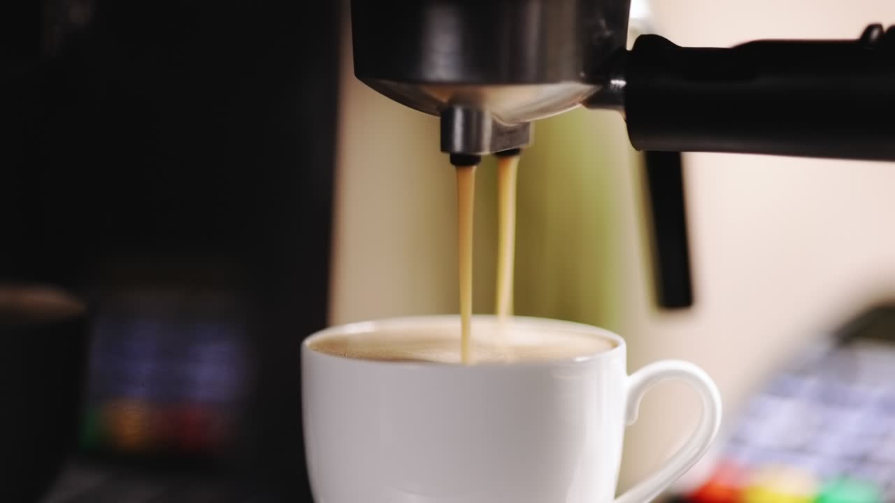 máquina de espresso vertiendo café. primer plano de espresso goteando en taza de café. espresso en una taza blanca. café sabroso. cafeína. cafetería en el fondo con terminal de máquina de tarjeta de crédito nfc