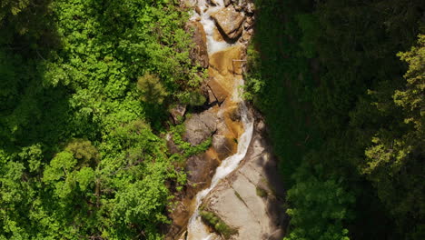 Aerial-of-a-small-mountain-creek-surrounded-by-a-green-forest