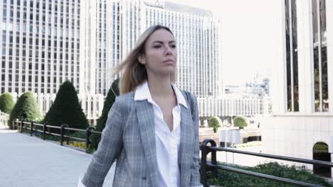 confident young businesswoman walking in financial district in city day