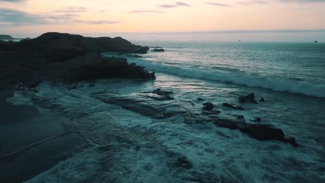 drone aerial view of waves crashing on the rocks of the shore, beach in lobitos coast in peru, south america.