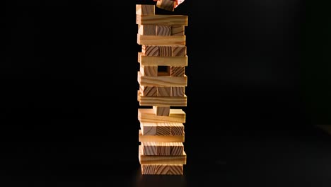 la mano quitando ladrillos de una torre