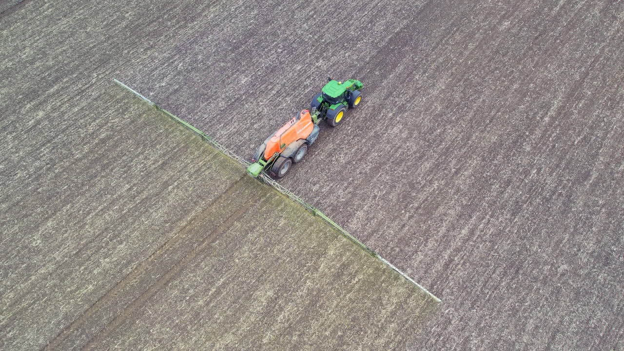 들판에 비료를 뿌리는 트랙터