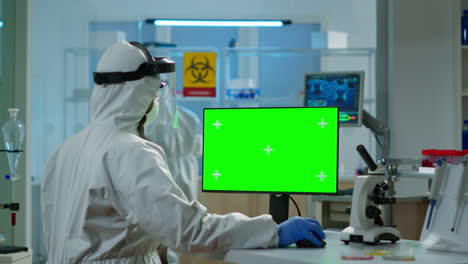 scientist man wearing protection suit typing on computer with green mockup