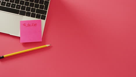 video of laptop with post it and pencil on red surface with copy space