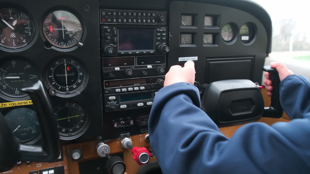Little child playing pilot in the cabin of light sport aircraft, childhood dreams of flying, closeup of instrument panel and moving the controls