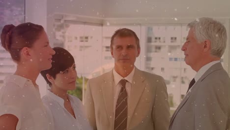partículas blancas flotando contra diversos hombres de negocios discutiendo juntos en la oficina