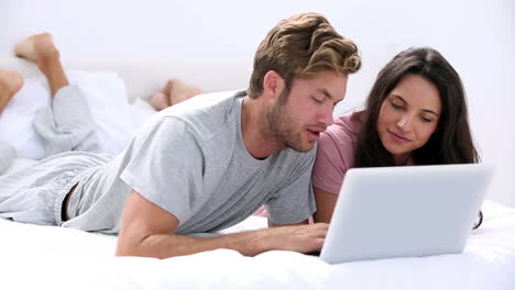 couple using the laptop lying bed