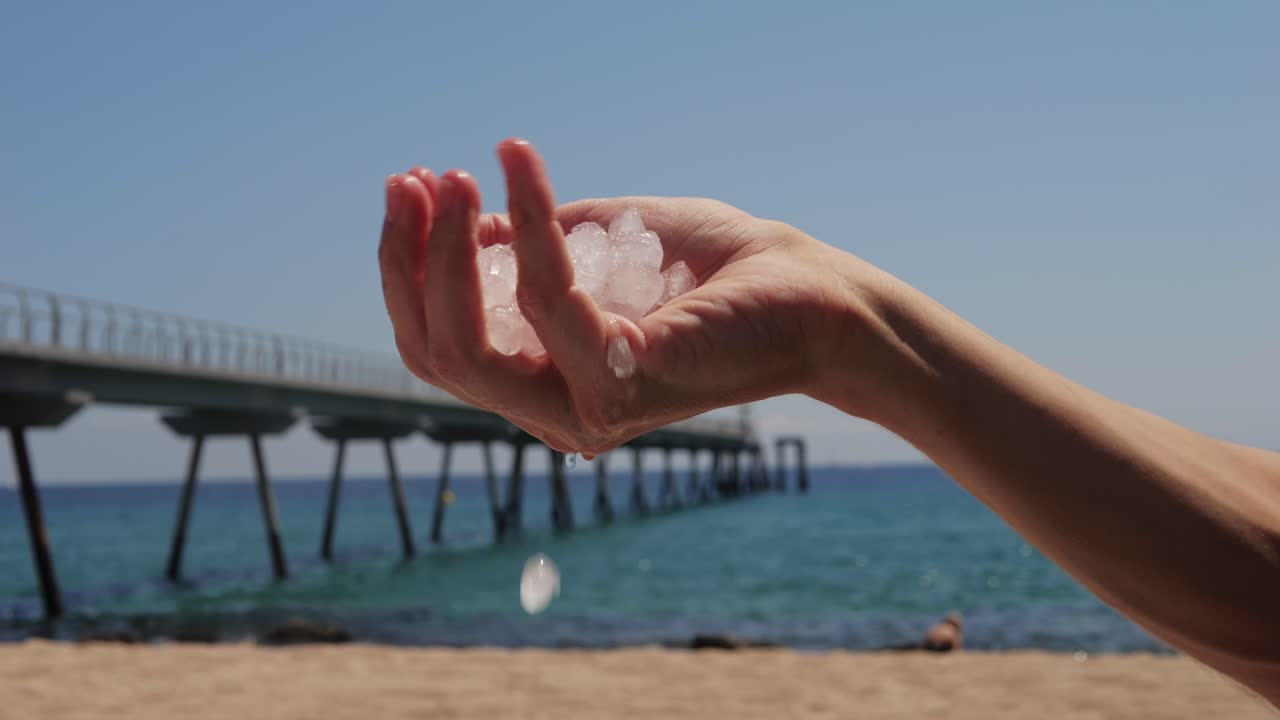 Ice melting in hand on a beach