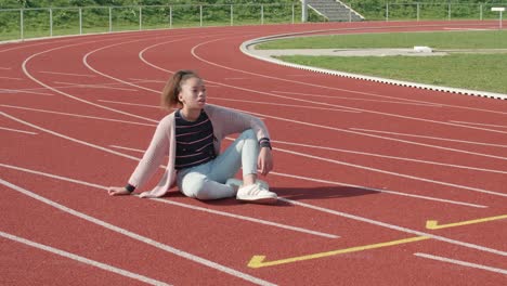 adolescente, joven afroamericana sentada exhausta en una pista de atletismo sola